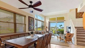 A spacious dining area with a wooden table and chairs, a ceiling fan, and large windows with blinds. - Na Hale O Keauhou Beach Views, Hot Tub & Pool (Kailua-Kona)