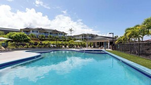 A rectangular swimming pool with a tiled edge, surrounded by lounge chairs and umbrellas, with buildings in the background. - Na Hale O Keauhou Beach Views, Hot Tub & Pool (Kailua-Kona)