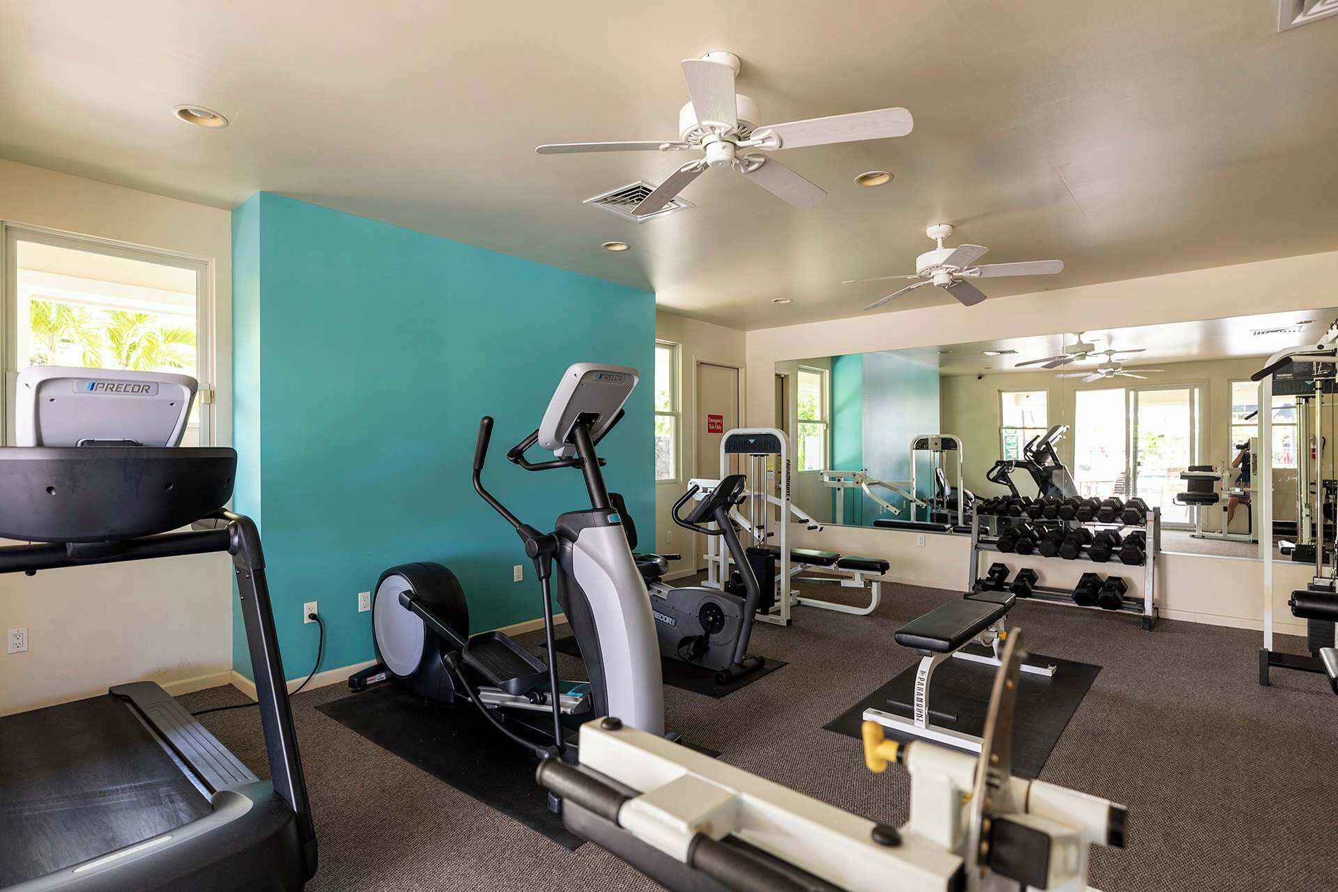 A gym with exercise equipment, a treadmill, and a mirrored wall.