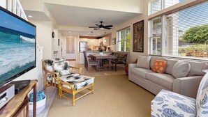 A spacious living room with a large TV, a dining area, and a kitchen in the background. - Na Hale O Keauhou Beach Views, Hot Tub & Pool (Kailua-Kona)