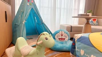 A cozy room with a blue tent, a green plush toy, and a blue cushion with a cartoon character.