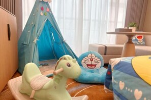Una habitación acogedora con una tienda azul, un peluche verde y un cojín azul con un personaje de dibujos animados.