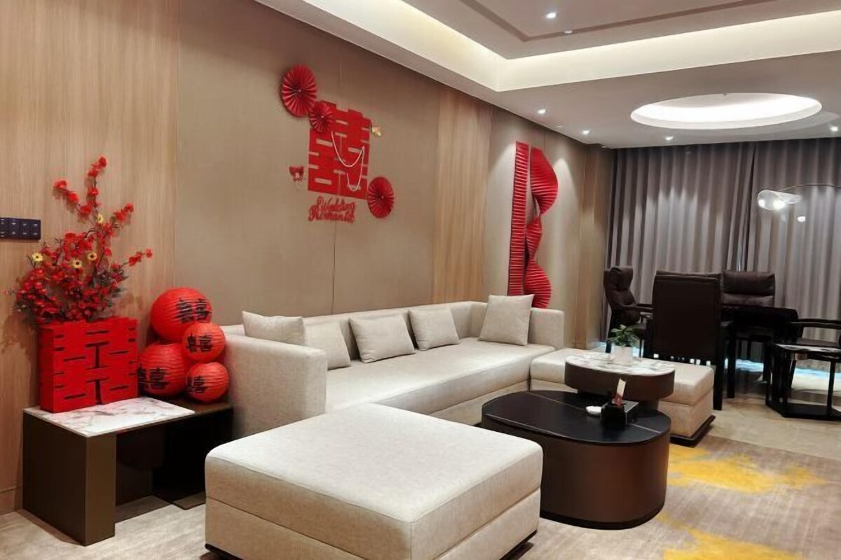 Una sala de estar moderna con un sofá seccional, una mesa de centro y elementos decorativos como faroles rojos y arte mural.