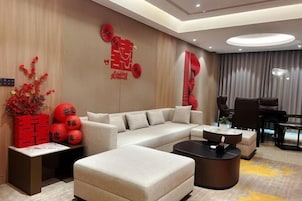 Una sala de estar moderna con un sofá seccional, una mesa de centro y elementos decorativos como faroles rojos y arte mural.