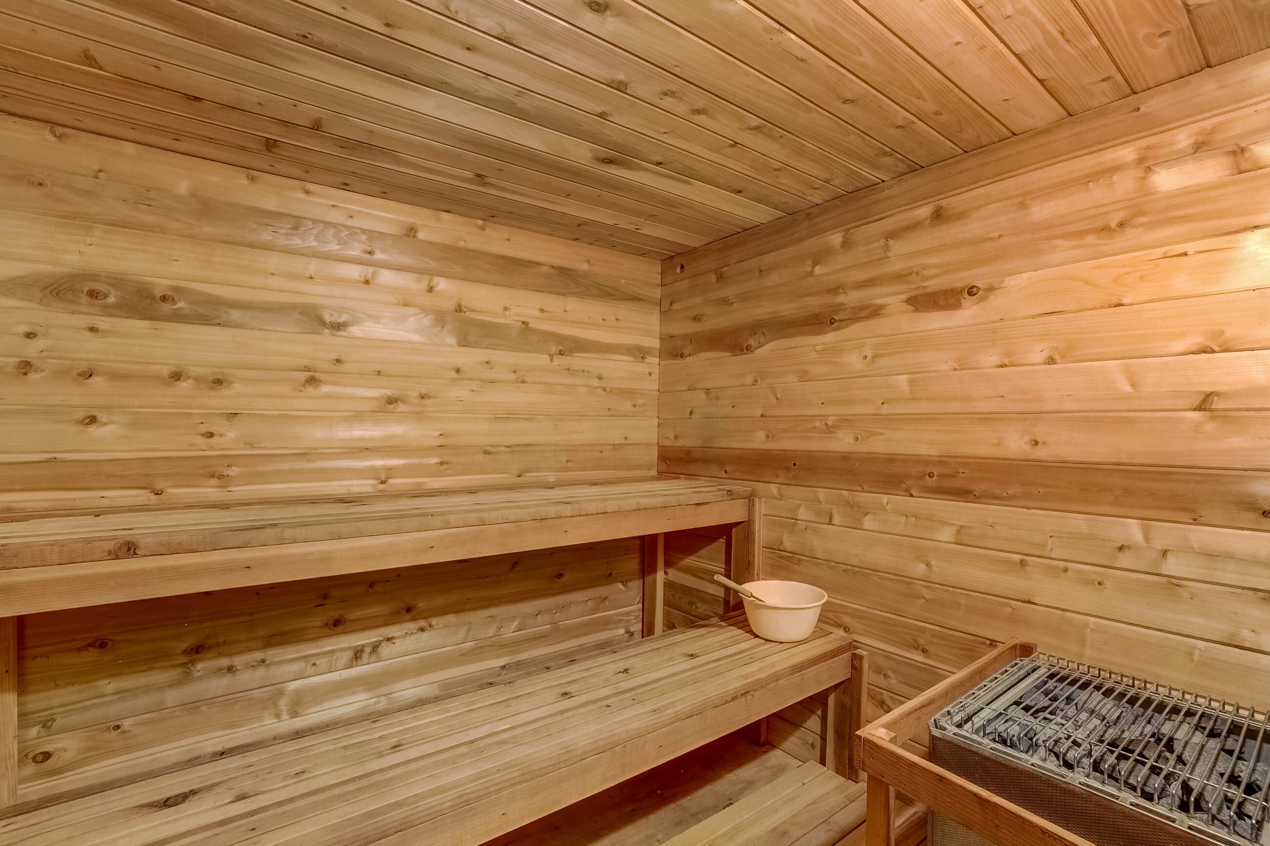 A wooden sauna with benches and a metal rack.