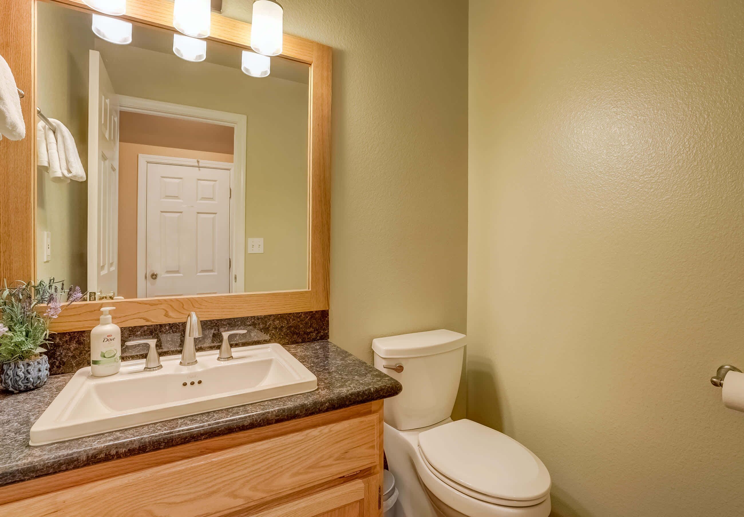 A bathroom with a sink, mirror, and toilet.