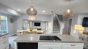 A modern kitchen with a central island, white cabinetry, and two pendant lights. - Hello Sunshine! 4 Bedroom w/Pool and Outdoor Bar (Tampa)