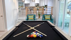 A pool table with balls and cues, a dining area with chairs and a table, and a view through a glass door. - Hello Sunshine! 4 Bedroom w/Pool and Outdoor Bar (Tampa)