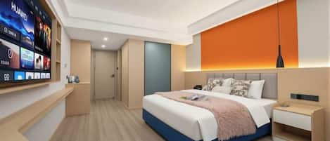 Una habitación de hotel moderna con una cama grande, un televisor montado en la pared y un escritorio con lámpara.