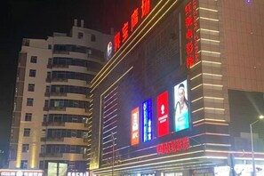 A multi-story building with illuminated signage and advertisements. - Ming Chao Holiday Hotel (Foshan)
