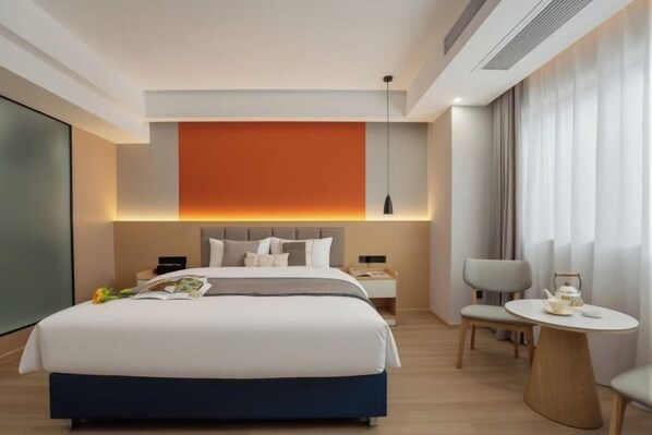 A modern hotel room with a large bed, bedside tables, a round table, and a view of the city. - Ming Chao Holiday Hotel (Foshan)