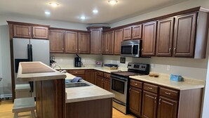 Una cocina con armarios de madera, electrodomésticos de acero inoxidable y una isla de madera con pileta.
