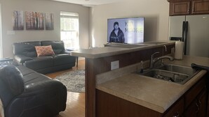Una cocina moderna con una isla integrada, un televisor de pantalla plana y armarios de madera.