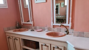 Une salle de bain avec deux lavabos, un miroir et un meuble avec des paniers.