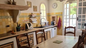 Une cuisine avec une table à manger, des chaises et une horloge au mur.