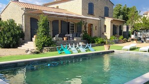 Une maison en pierre avec une piscine, du mobilier d’extérieur et une pelouse bien entretenue.