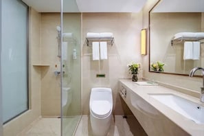 Un baño moderno con ducha de vidrio, inodoro blanco, lavabo con espejo y perchero para toallas.