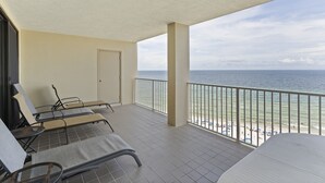 A balcony with lounge chairs, a door, and a view of the beach and ocean. - White Caps 1102 by Liquid Life (Orange Beach)