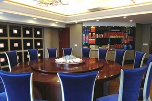 A conference room with a round table, blue chairs, and a floral centerpiece. - Tiancheng Plaza Hotel (Neijiang)
