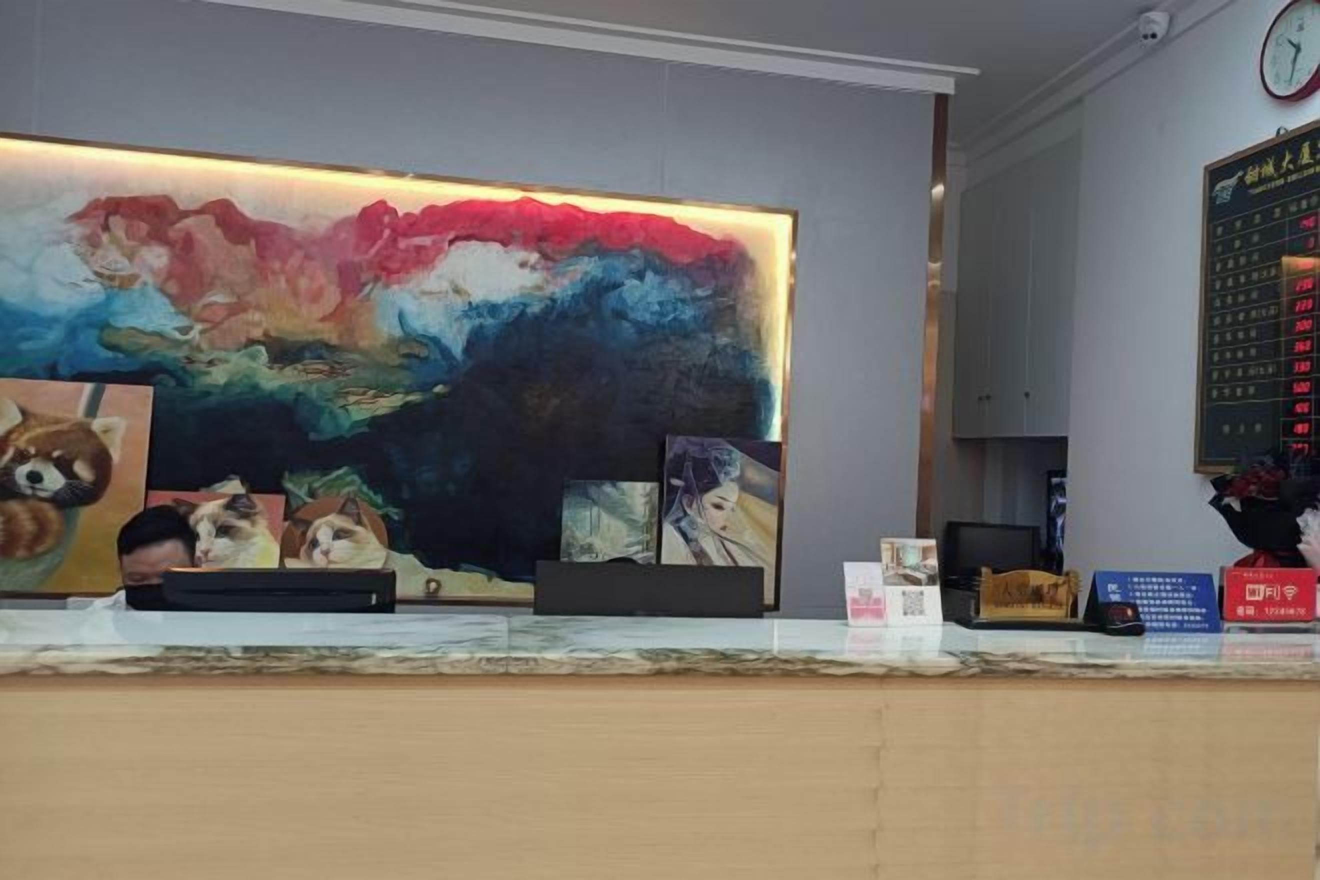 A reception desk with a large abstract painting, a clock, and a digital display.
