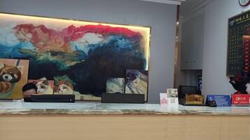 A reception desk with a large abstract painting, a clock, and a digital display.