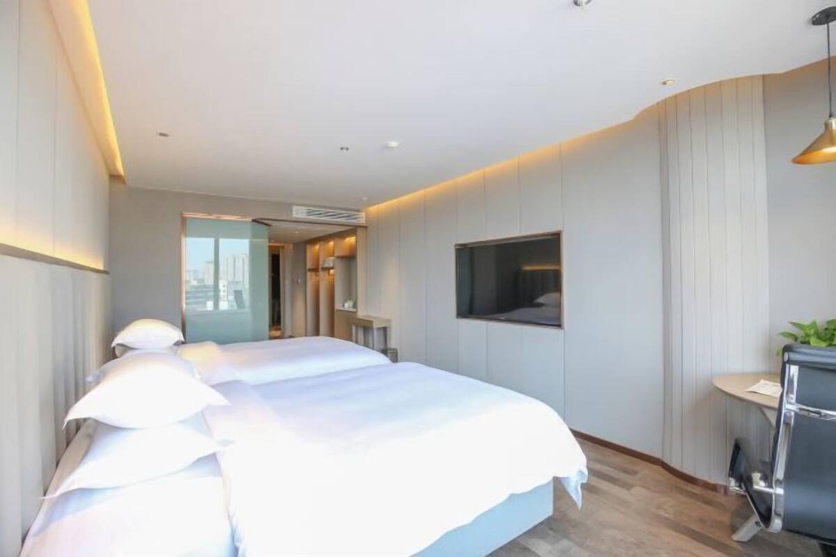 Ein Hotelzimmer mit einem großen Bett, einem Schreibtisch, einem Fernseher und Blick auf die Stadt.