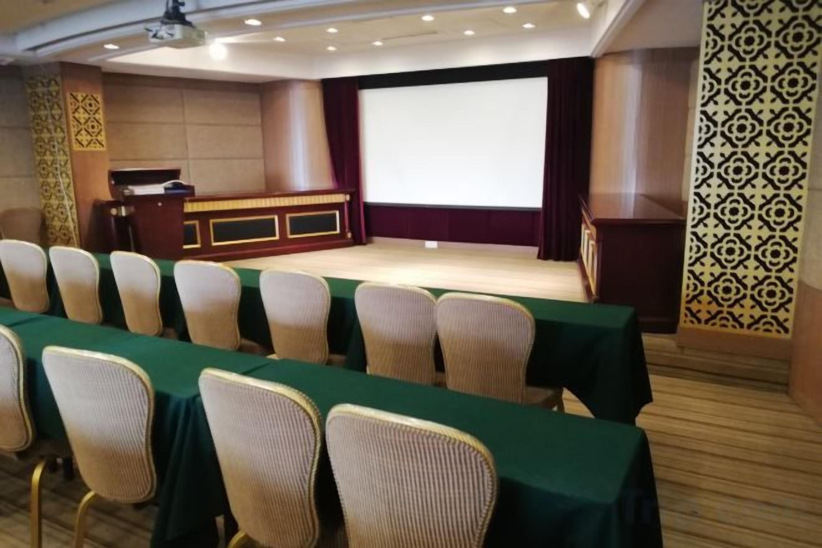 A conference room with a stage, rows of chairs, and a podium.