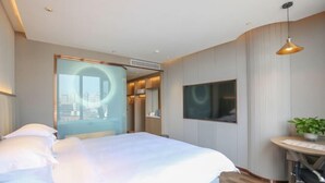 A modern hotel room with a bed, a TV, a small table with a plant, and a city view through a glass door. - Tiancheng Plaza Hotel (Neijiang)