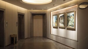 A hallway with a wooden floor, a circular light fixture on the ceiling, and three framed artworks on the wall. - Tiancheng Plaza Hotel (Neijiang)