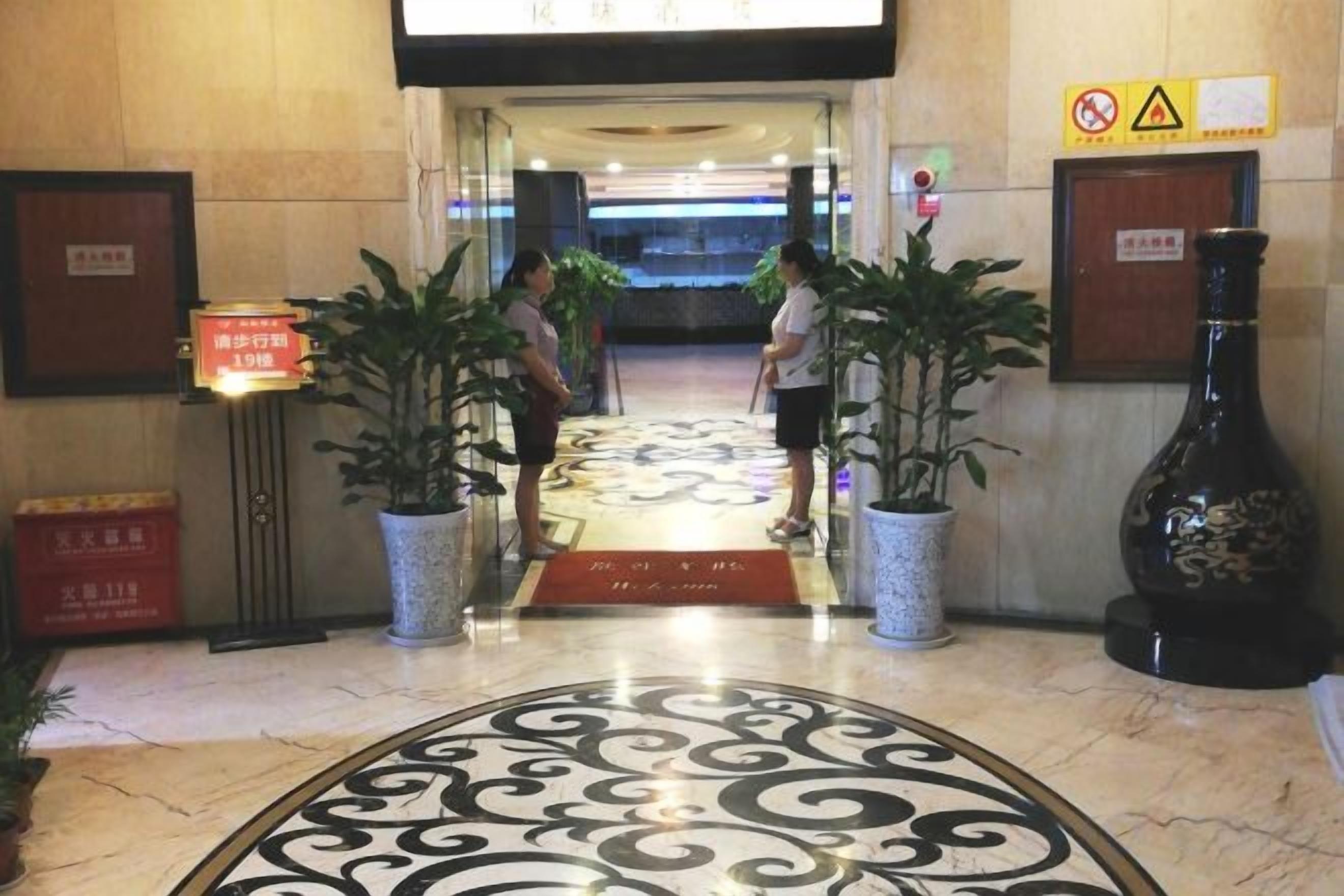 Un vestíbulo de hotel con piso de mármol, plantas en macetas y una botella de licor.