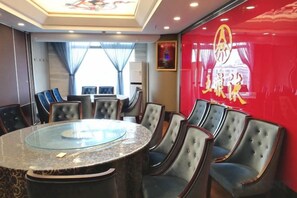 Ein Konferenzraum mit einem Glastisch, umgeben von Stühlen, einer roten Wand mit einem Logo und einem Fenster mit Vorhängen.