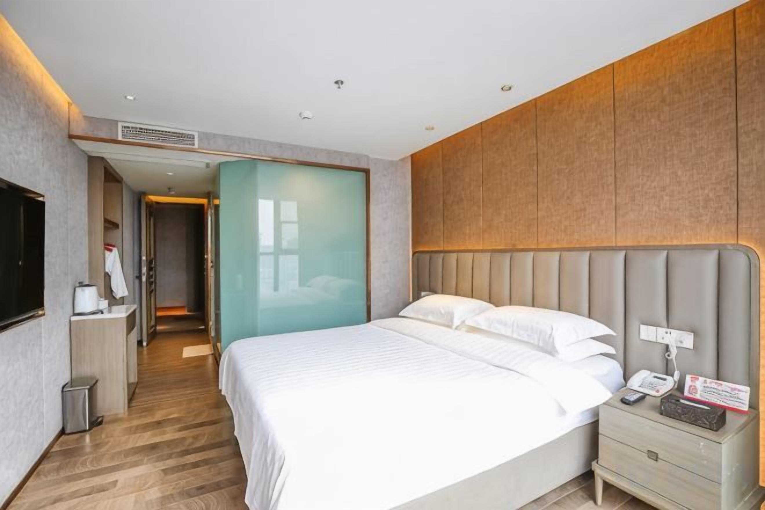 A hotel room with a bed, bedside table, and a television.