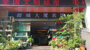 A building entrance with a sign in Chinese characters, potted plants, and a staircase leading up to the entrance.