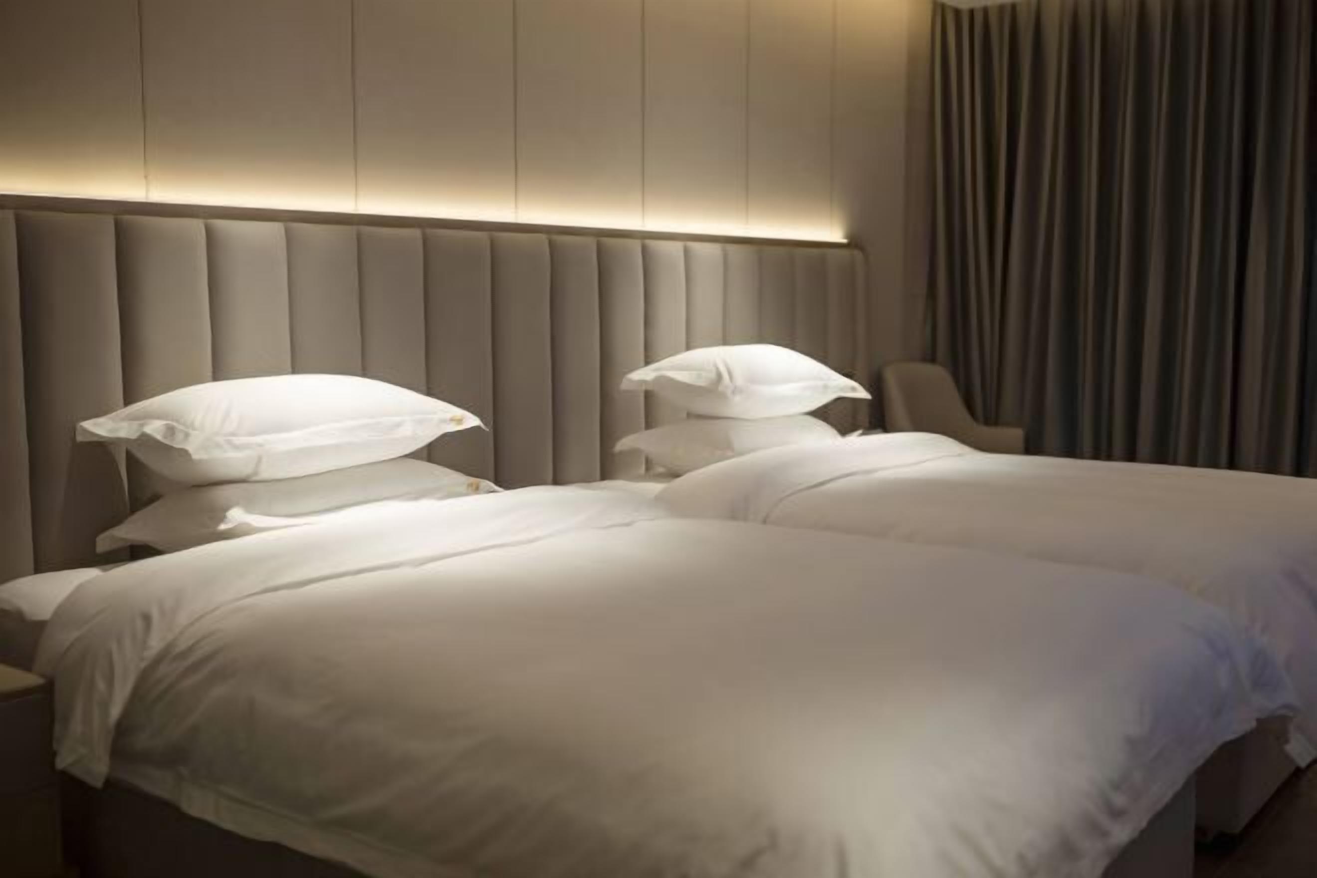 A hotel room with a large bed, a padded headboard, and a chair.