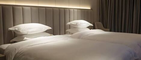 A hotel room with a large bed, a padded headboard, and a chair.