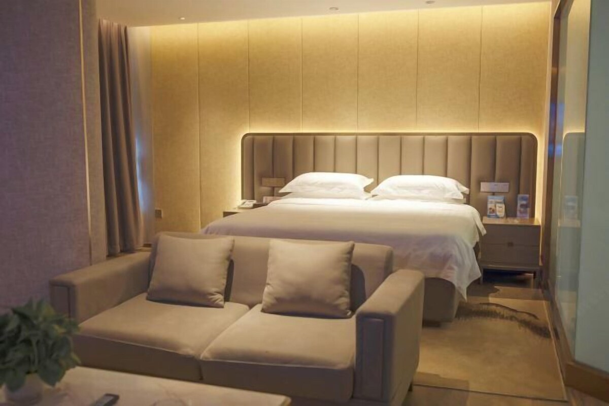 Een hotelkamer met een bed, twee nachtkastjes, een bank en een kleintje tafeltje met een plant.