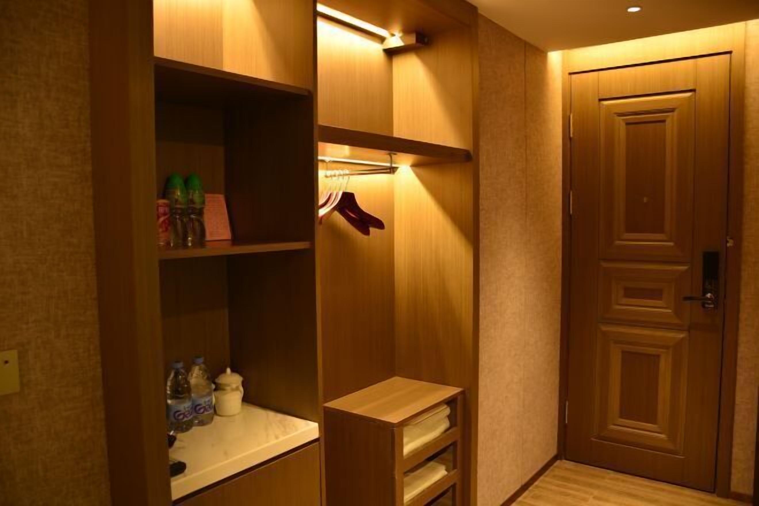 Habitación de hotel con un armario de madera, un espejo y una puerta.