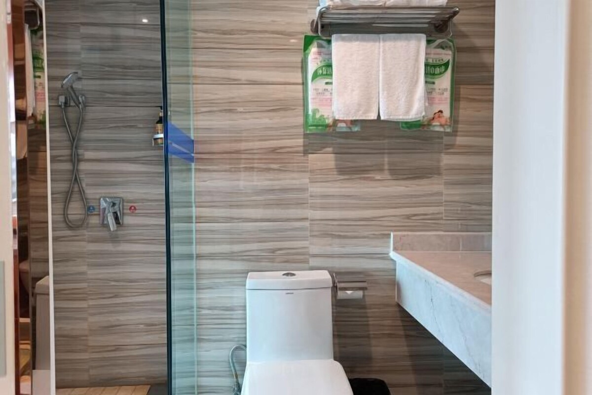 Een moderne badkamer met een douchecabine van glas, een toilet en een wastafel.