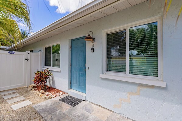 A house with a blue door, a small porch with a potted plant, and a mailbox.