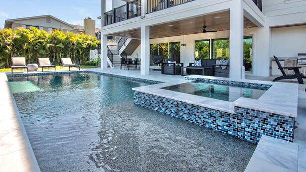 A two-story house with a swimming pool, outdoor furniture, and a covered patio area.