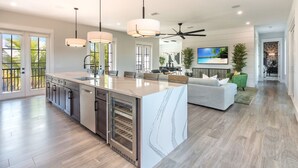 A modern kitchen with a large island, pendant lights, and a ceiling fan.