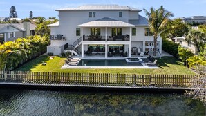 A two-story house with a swimming pool, a covered patio, and a fenced yard.