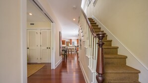 A hallway with wooden flooring, a staircase with a wooden handrail, and a door leading to a room. - Papa's Casita in Downtown Key West (Key West)