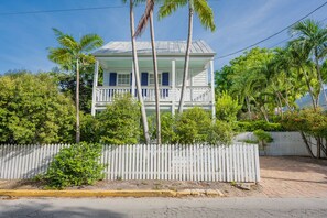 A two-story house with a balcony, surrounded by a white picket fence and palm trees. - Papa's Casita in Downtown Key West (Key West)