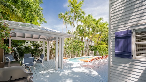 A covered outdoor deck with a pool, lounge chairs, and a barbecue grill. - Papa's Casita in Downtown Key West (Key West)