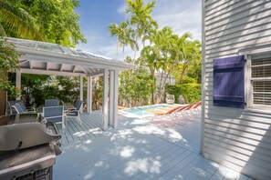 A covered outdoor deck with a pool, lounge chairs, and a barbecue grill. - Papa's Casita in Downtown Key West (Key West)