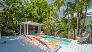 A pool area with lounge chairs and a covered seating area. - Papa's Casita in Downtown Key West (Key West)
