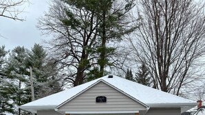 A single-story house with a front porch, a garage, and a snow-covered roof. -  The Bungalow on State (Eau Claire)