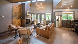 Amplia sala de estar con chimenea, asientos cómodos y una cocina equipada con electrodomésticos modernos.