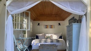 Une chambre confortable avec un plafond en bois, un lit recouvert de linge de lit blanc, une commode et une petite table avec une chaise.